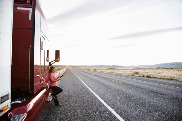 female-truck-driver-standing-next-to-the-cab-of-he-VNTME5A
